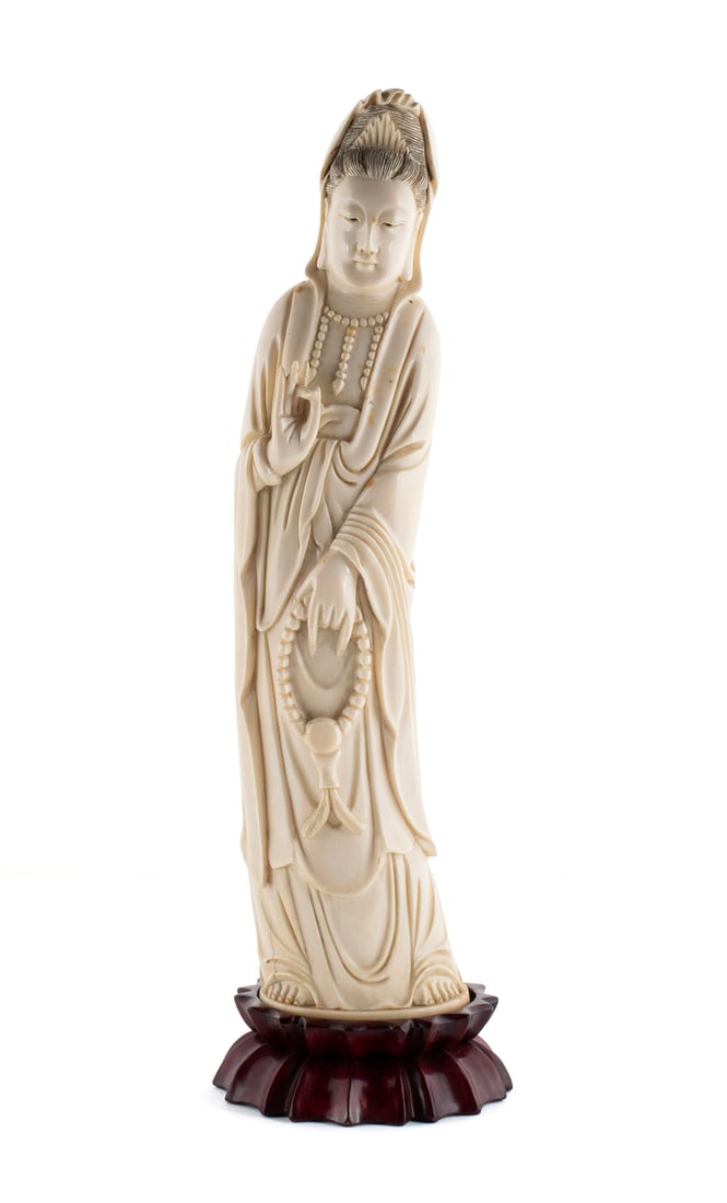 CHINESE CARVED FIGURE OF GUANYIN: CHINESE CARVED FIGURE OF GUANYIN Late 19th/early 20th century. Standing figure of Guanyin, the right hand raised in Shuni Mudra, the left hand lowered holding prayer beads, character mark underfoot.