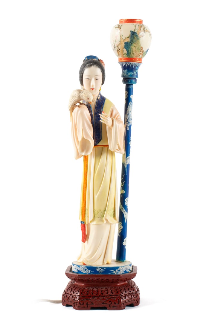 CARVING OF A BEAUTY, MOUNTED AS LAMP: CARVING OF A BEAUTY, MOUNTED AS LAMPChinese, early 20th century. Polychrome decorated carved figure of a woman with a bird perched on her shoulder, next to lantern on pole resting on red lacquer base.