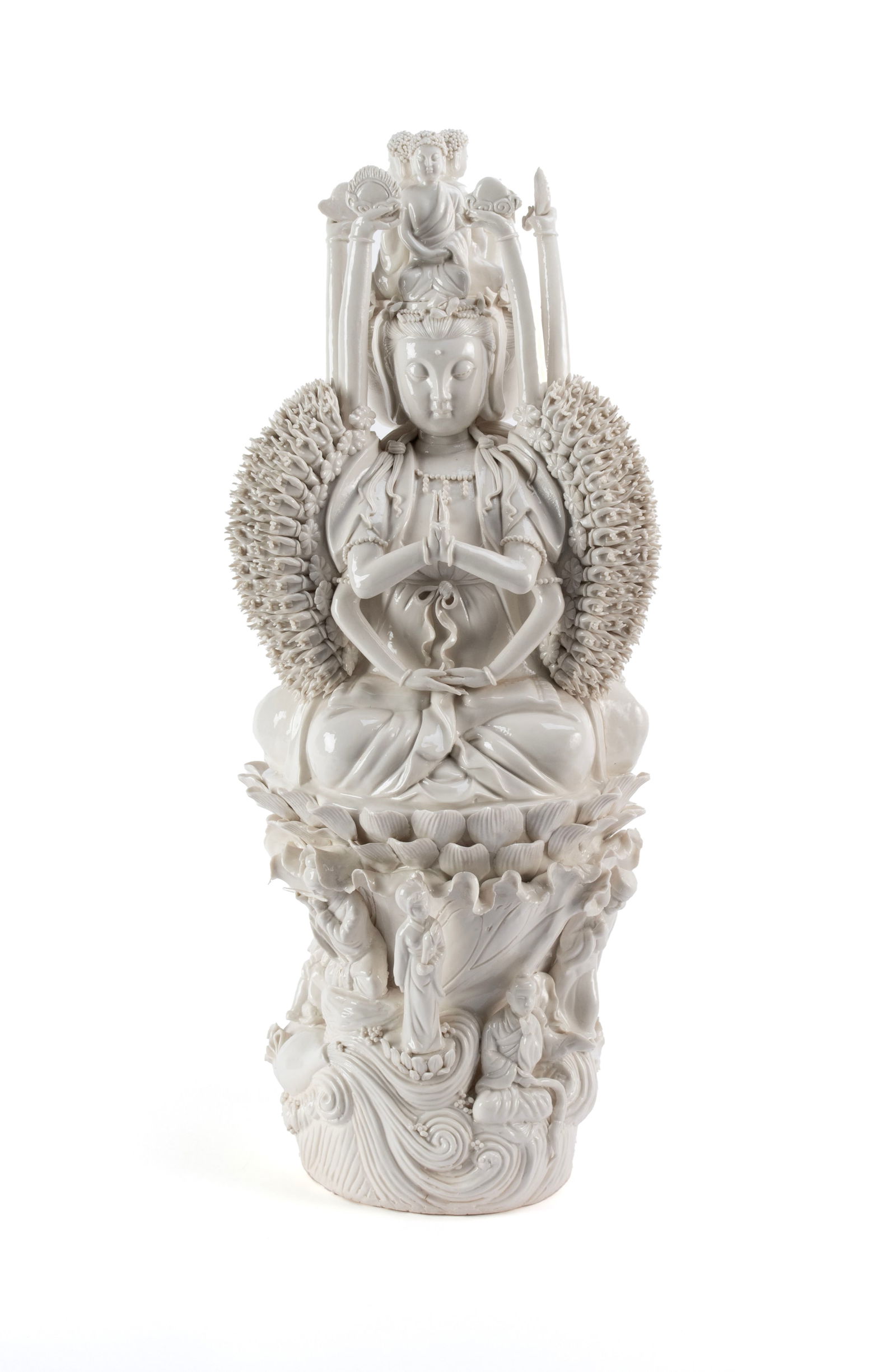 BLANC DE CHINE QUAN YIN: BLANC DE CHINE QUAN YINChinese, 20th century. Depicts Quan Yin seated on a lotus flower, the goddess of compassion in the thousand hand form, figures around the bottom.23 x 9 1/2 in. (58.4 x 24.1 cm.)