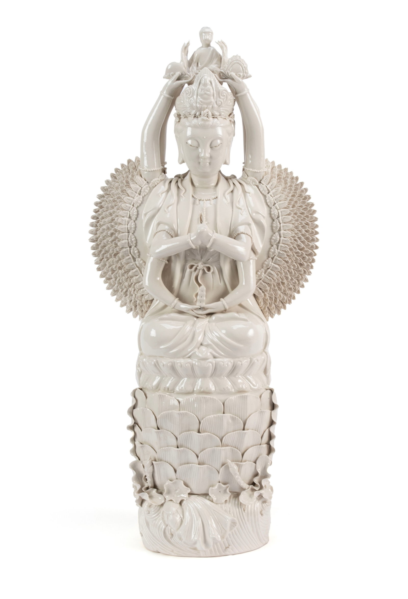 BLANC DE CHINE QUAN YIN: BLANC DE CHINE QUAN YINChinese, 20th century. Depicts a seated Quan Yin, the goddess of compassion in the thousand hand form, with a figure on her head, on a tall lotus flower pedestal.26 x 12 in. (67