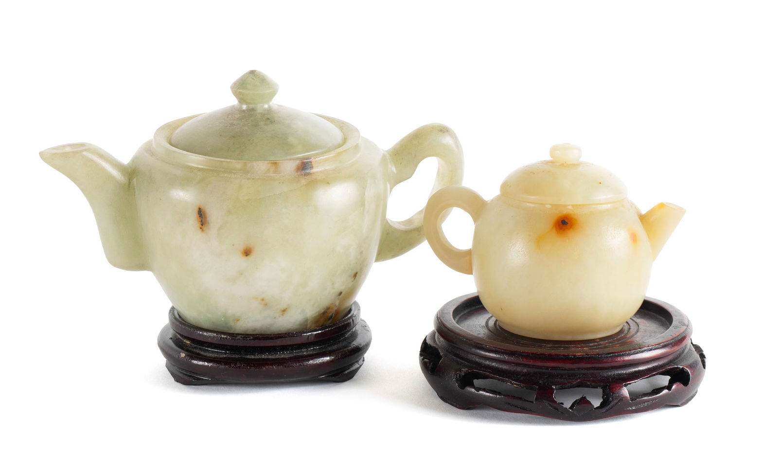 TWO CHINESE CARVED JADE TEAPOTS: TWO CHINESE CARVED JADE TEAPOTS Early 20th century. Two diminutive teapots with pierced lid finials. 3 1/2 x 3 1/2 x 6 in. (8.9 x 8.9 x 15.2 cm.), 2 1/2 x 2 1/2 x 3 1/2 in. (6.4 x 6.4 x 8.9 cm.)