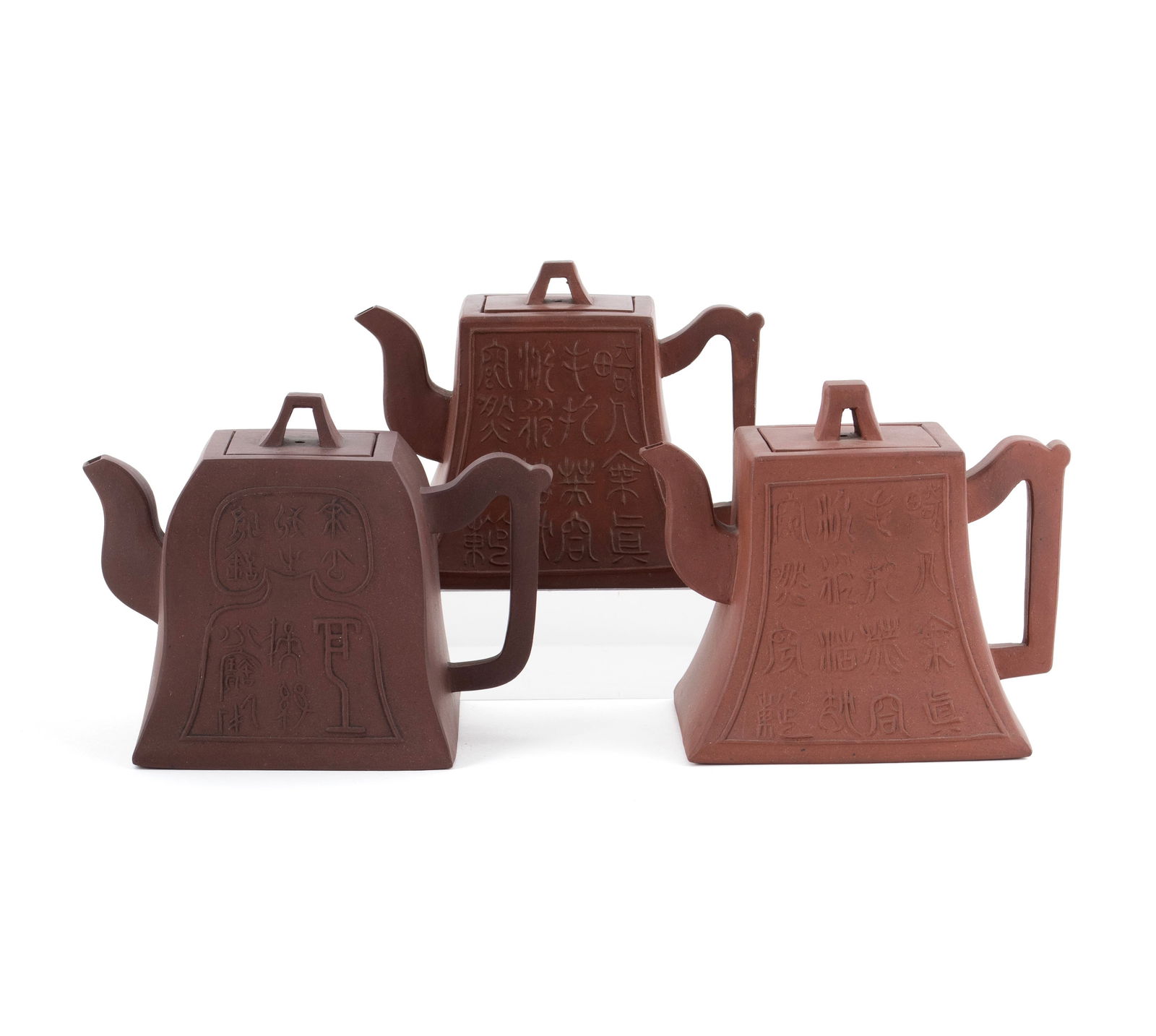 THREE YIXING CALLIGRAPHY TEAPOTS: THREE YIXING CALLIGRAPHY TEAPOTS20th century. Three (3) teapots with archaic calligraphy to one side, each marked to lid and underside.Largest: 5 in. (12.7 cm.)