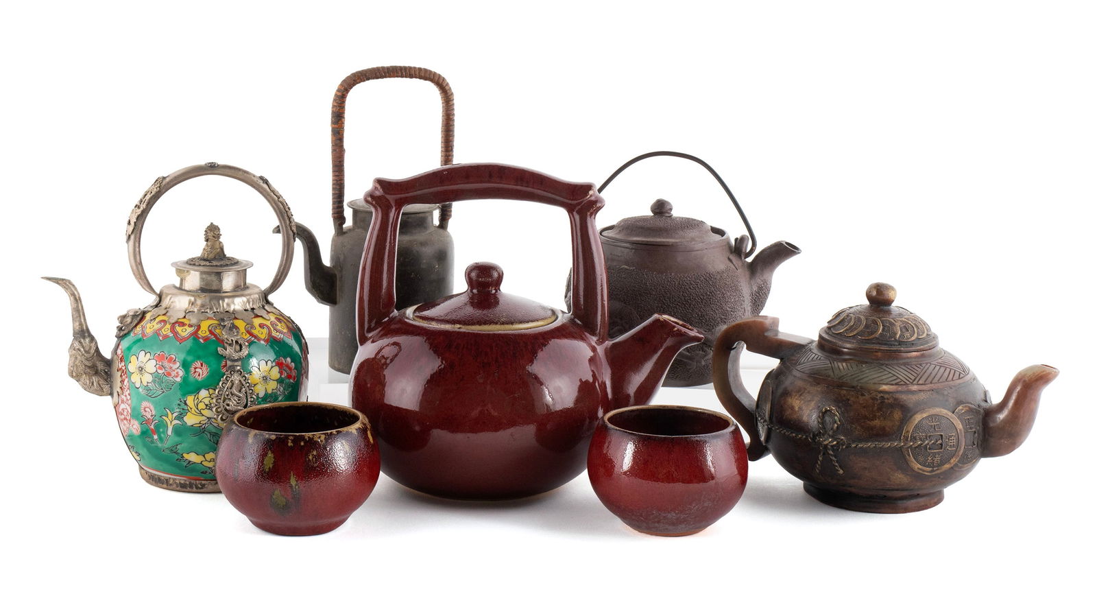 FIVE ASIAN TEAPOTS: FIVE ASIAN TEAPOTS20th century. Japanese aluminum foo-dog teapot, pewter teapot with wrapped handle, carved soapstone teapot, Tibetan mounted porcelain teapot and a Chinese red glazed pottery teapot w