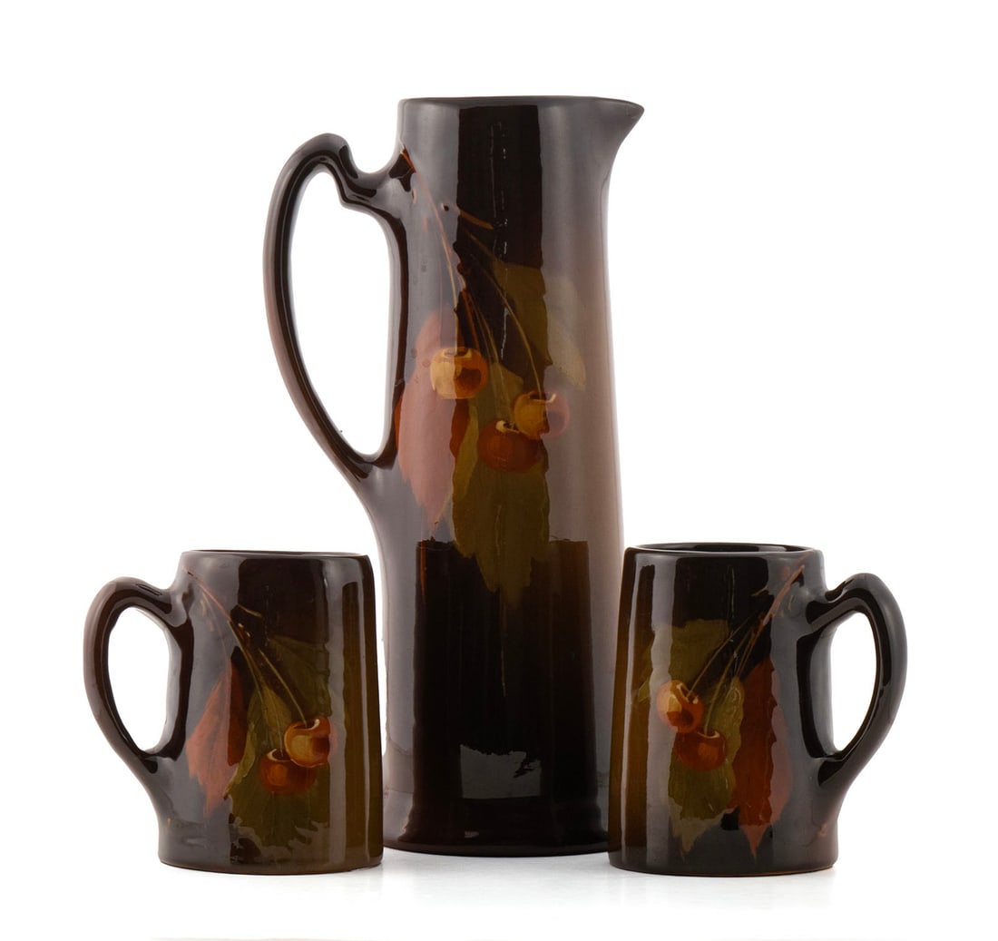 JB OWENS 'UTOPIAN' MUG AND PITCHER SET: JB OWENS 'UTOPIAN' MUG AND PITCHER SETAmerican, early 20th century. Three pieces with cherry decoration, all marked on underside.Largest: 12 1/4 in. (31.1 cm.)