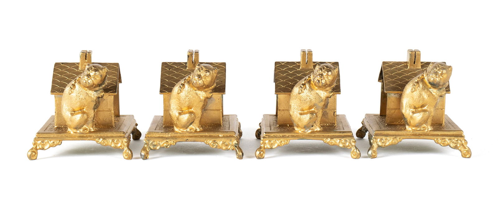 FOUR BULLDOG NAPKIN HOLDERS: FOUR BULLDOG NAPKIN HOLDERS American, early 20th century, in the manner of Simpson, Hall & Miller although not marked as such. Each with a gilt finish in the form of a bulldog seated beside his