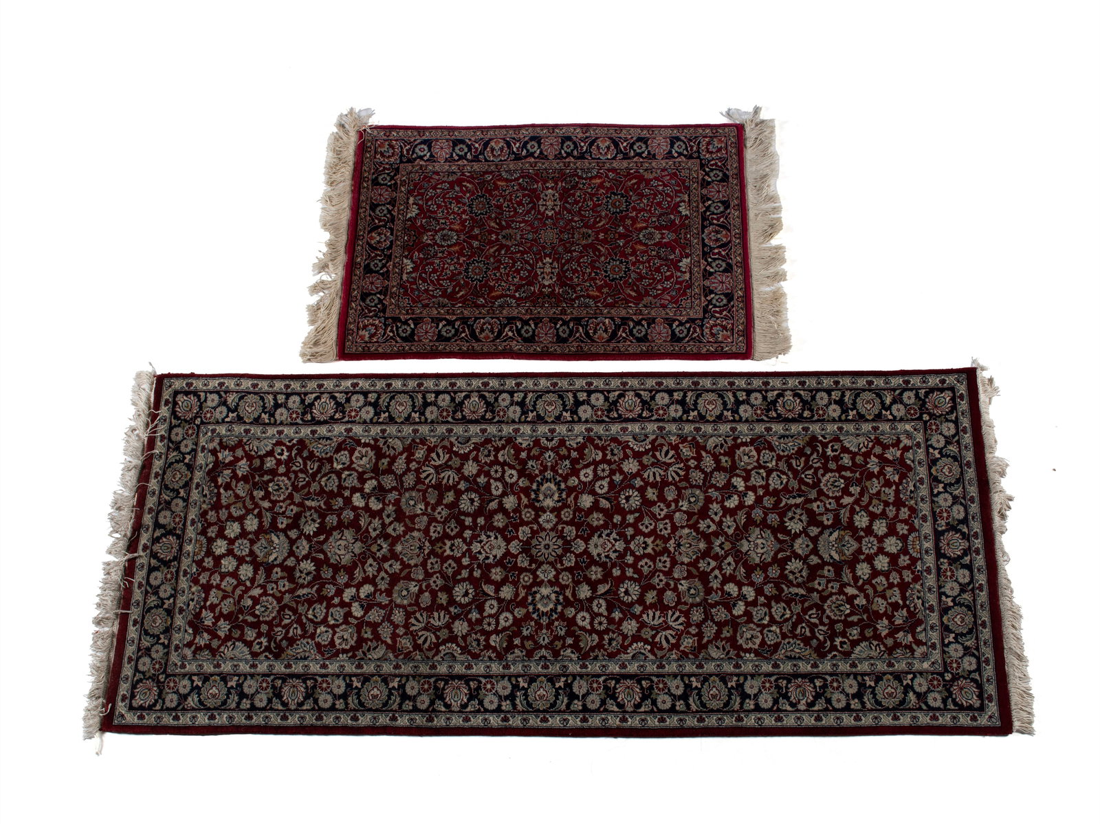 TWO TABRIZ DESIGN AREA RUGS: TWO TABRIZ DESIGN AREA RUGS20th century. One a long rug with flowering vines throughout the deep red field, navy border with ivory guard borders. The other scrolling foliate vines throughout the red f