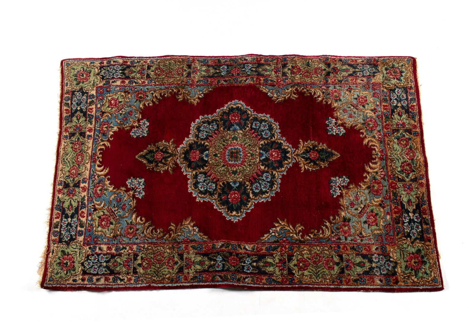 KERMAN AREA RUG: KERMAN AREA RUG Persian, 3rd quarter 20th century. Colorful rose filled foliate pole medallion centers the open red field with floral decorated sky-blue corners, matching floral decorated panels to