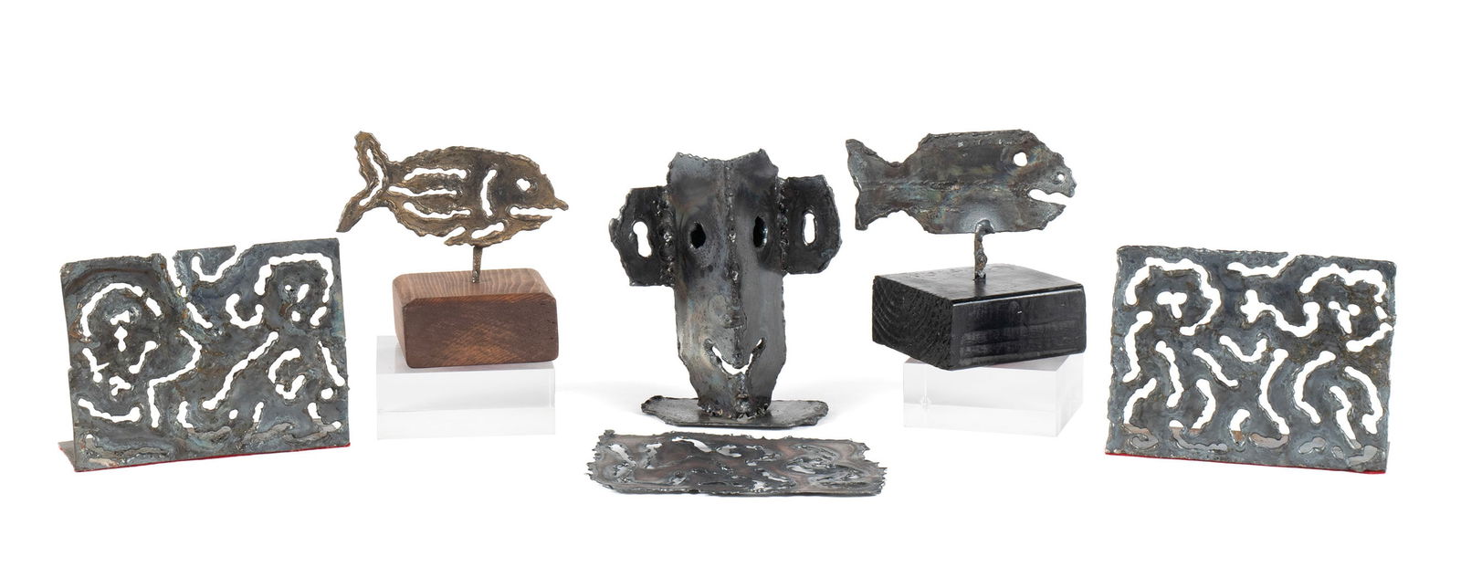 CAROLE ROBERTS (AMERICAN, B. 1940): Carole RobertsAmerican, b. 1940Cut steelSix (6) pieces including two (2) fish sculptures mounted on wooden blocks, a pair of abstract cut bookends with another matching flat plate, and a mask, all uns