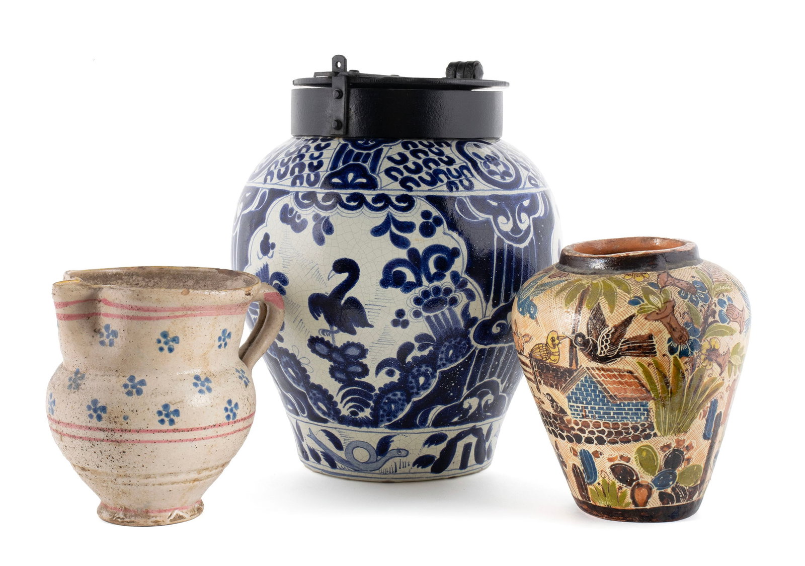 THREE MEXICAN CERAMICS: THREE MEXICAN CERAMICS 20th century. Including a Talavera blue and white jar with metal lid, a Tlaquepaque jar, both signed on underside, and a faience pitcher. Tallest: 13 in. (33 cm.)
