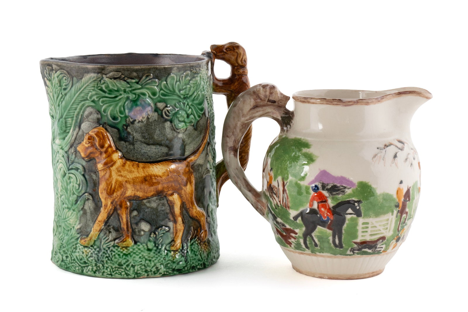 TWO HUNT PITCHERS: TWO HUNT PITCHERS Including a majolica pitcher with dogs, and a Wedgwood 'John Peel' style pitcher, unmarked. Larger: 7 1/2 in. (19.1 cm.)