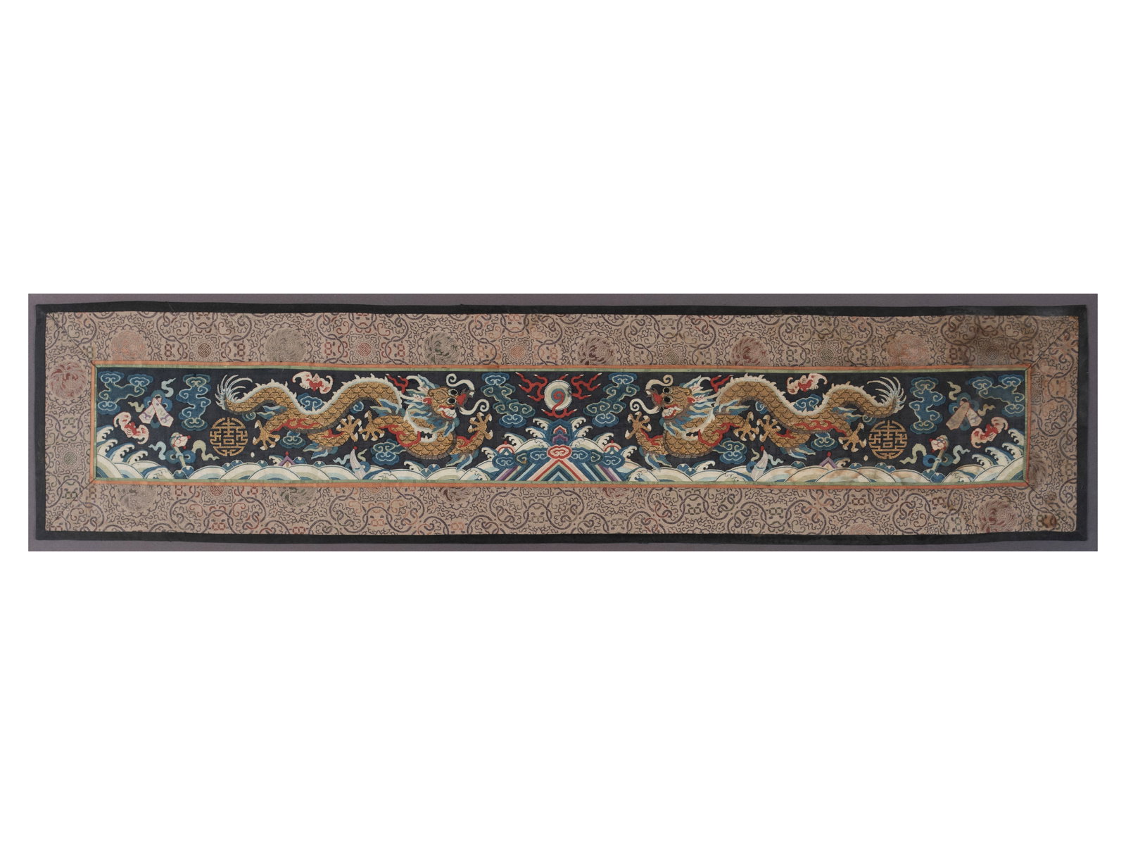 CHINESE EMBROIDERED DRAGON ROBE PANEL: CHINESE EMBROIDERED DRAGON ROBE PANEL Qing. Pair of five toed dragons with central flaming pearl surrounded by auspicious symbols within clouds, framed. 7 1/4 x 32 in. (18.4 x 81.3 cm.), Frame: 10 x