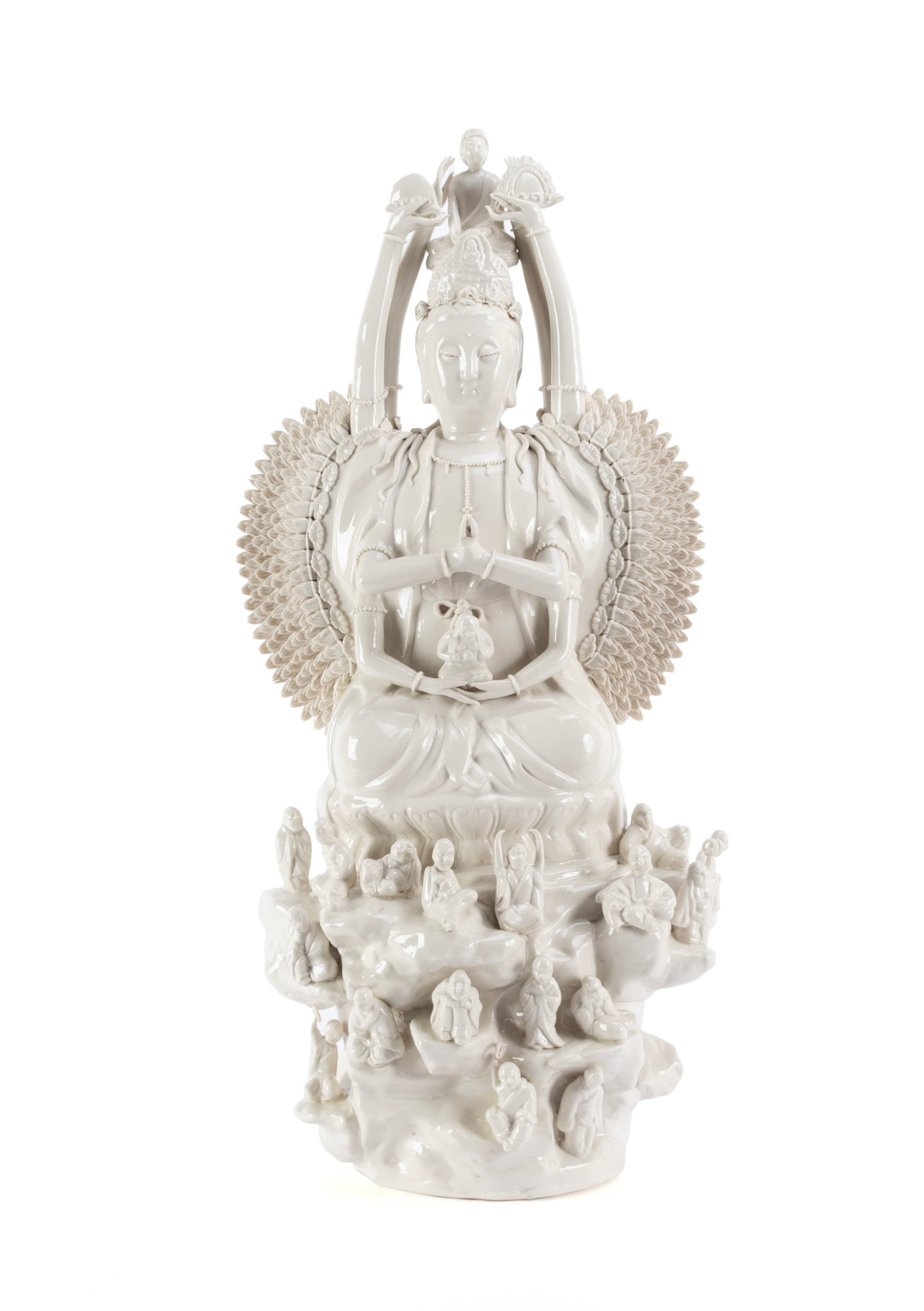 BLANC DE CHINE BODHISATTVA: BLANC DE CHINE BODHISATTVA Chinese, 20th century. Depicts Quan Yin, the goddess of compassion, in the thousand-arm form, with a Buddha figure a top her head, seated on a rocky base surrounded by