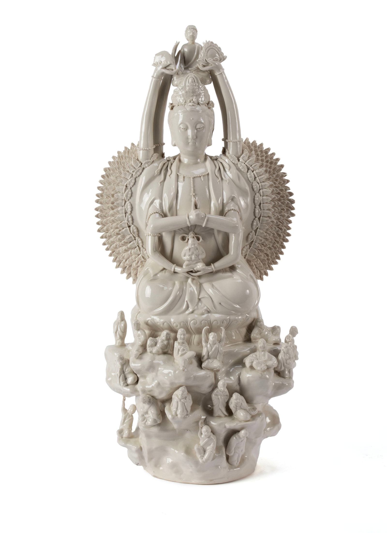 BLANC DE CHINE BODHISATTVA: BLANC DE CHINE BODHISATTVA Chinese, 20th century. Depicts Quan Yin, the goddess of compassion, in the thousand-arm form, with a Buddha figure a top her head, seated on a rocky base surrounded by