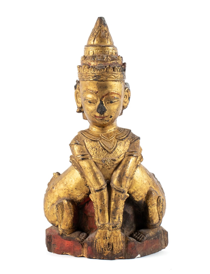 BURMESE GILTWOOD MANUSSIHA FIGURE: BURMESE GILTWOOD MANUSSIHA FIGURE Southeast Asian, 18th/19th century. Seated carved wooden figure wearing a conical hat, hands down to the ground in front, gilt with red highlights. 14 1/4 x 8 x 4