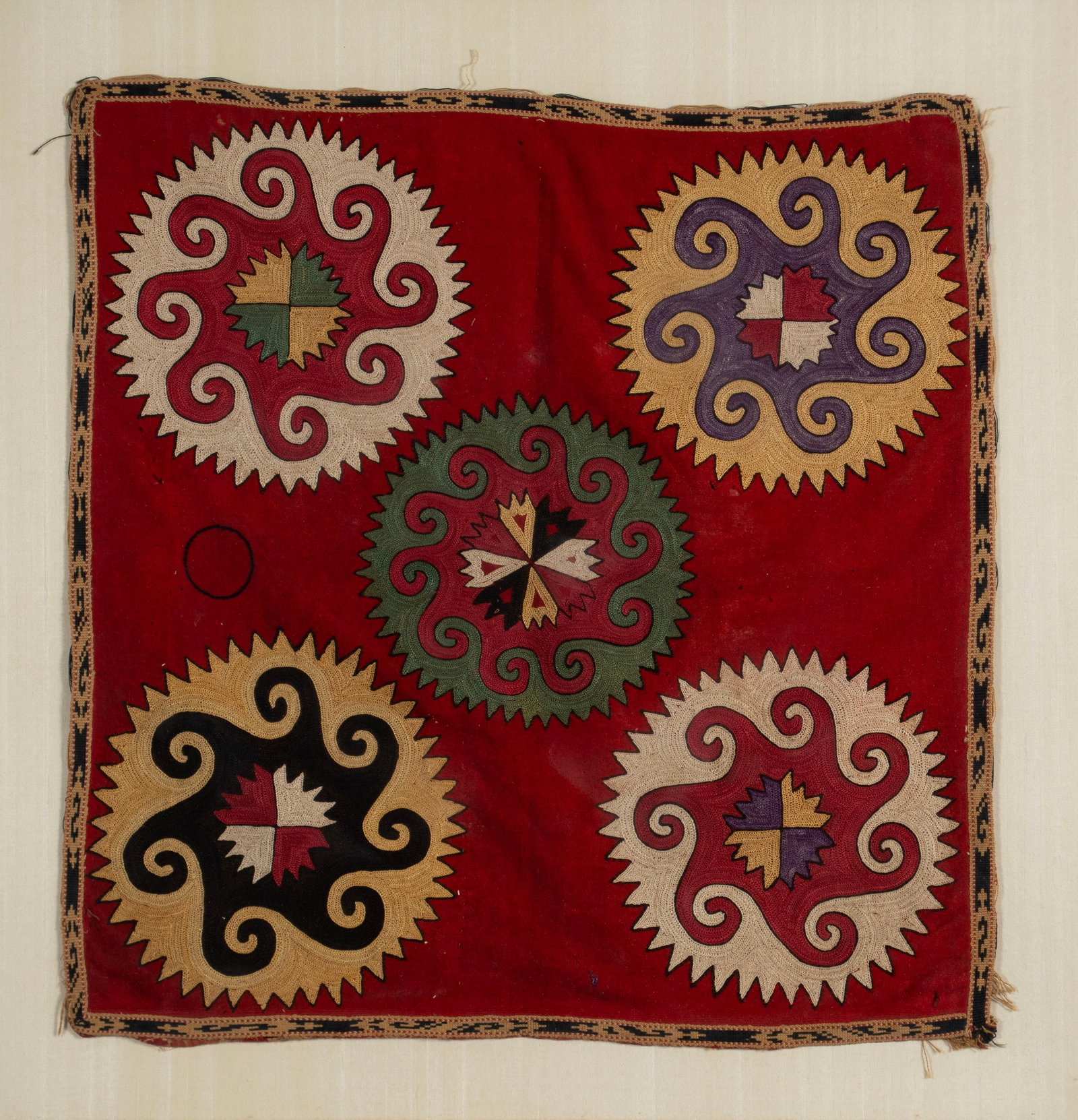 LAKAI ILGICH TEXTILE: LAKAI ILGICH TEXTILE Uzbekistani, 19th/20th century, chain stitched. Colorful spiraling geometric forms representing astragal images, on a red field with thin geometric outer border. 23 x 22 in. (58.4