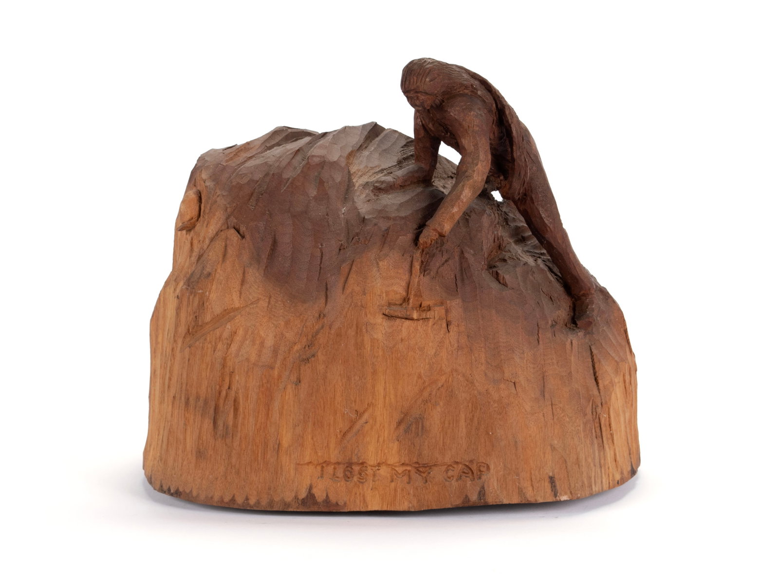 UTE SCULPTURAL CARVING: UTE SCULPTURAL CARVING Native American, early 20th century, wood. Carved near the base with the title "I Lost My Cap", showing a figure reaching as he scales a summit. 11 1/4 x 13 1/2 x 11 3/4 in. (28