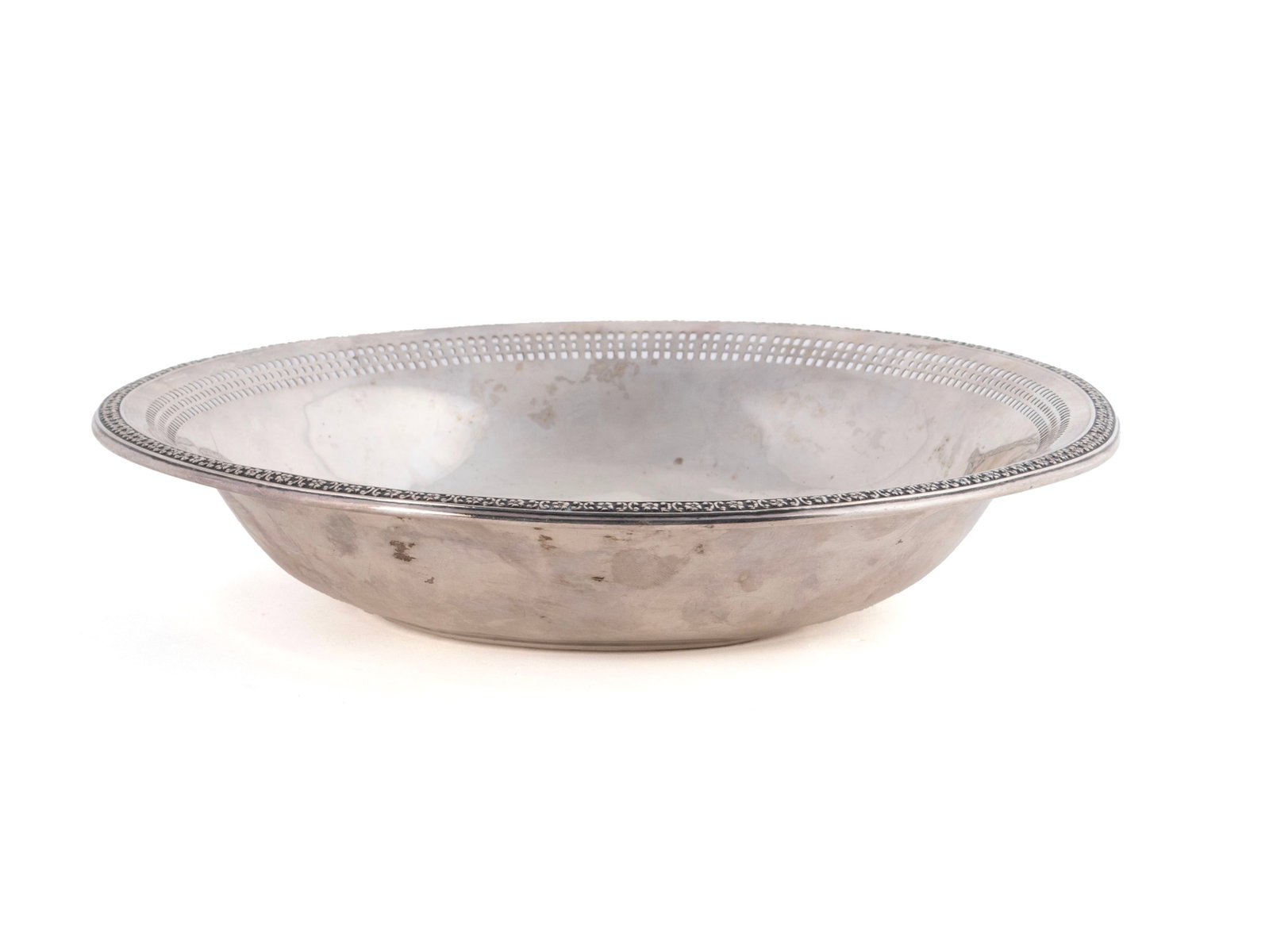 REED & BARTON STERLING SILVER BOWL: REED & BARTON STERLING SILVER BOWL American, 20th century. Floral decorated rim with reticulated band below, marked on underside. 140 grams. 1.60 x 8.30 x 8.30 in. (4.1 x 21.1 x 21.1 cm.)