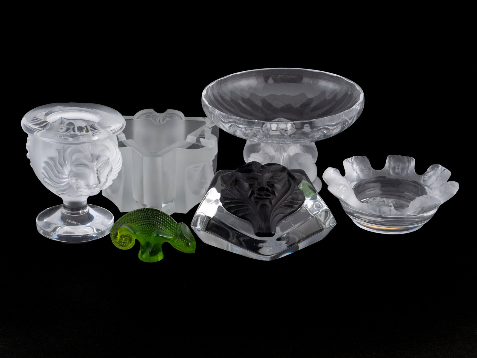 SIX LALIQUE PIECES: SIX LALIQUE PIECES French, 20th century. Including a green lizard figure, a satyr paperweight with ebonized mask on the clear ground, a diminutive vase with two lion masks to the sides, a triangular