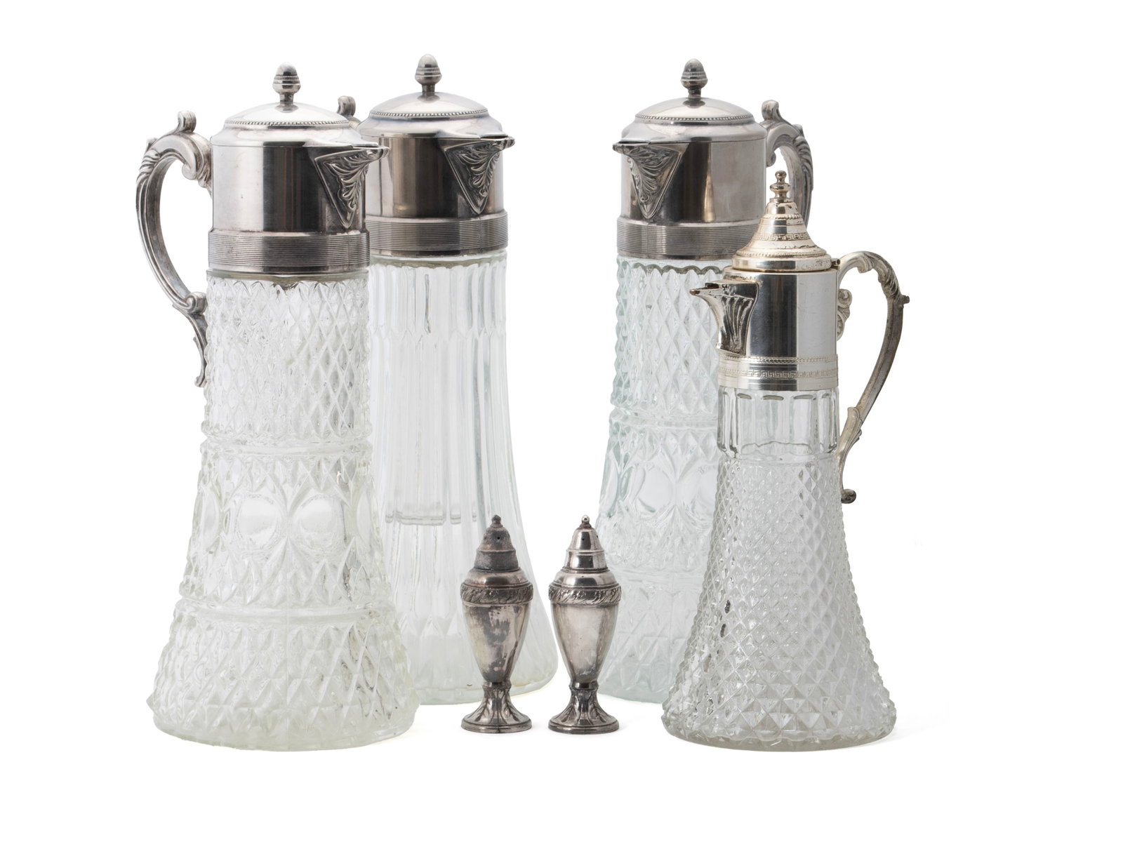 GROUP OF EWERS AND SHAKERS: GROUP OF EWERS AND SHAKERS American, 20th century. Four lidded ewers, each with plated silver handles and lids to the cut glass bodies. Together with a pair of plated silver shakers. Tallest: 14 in.