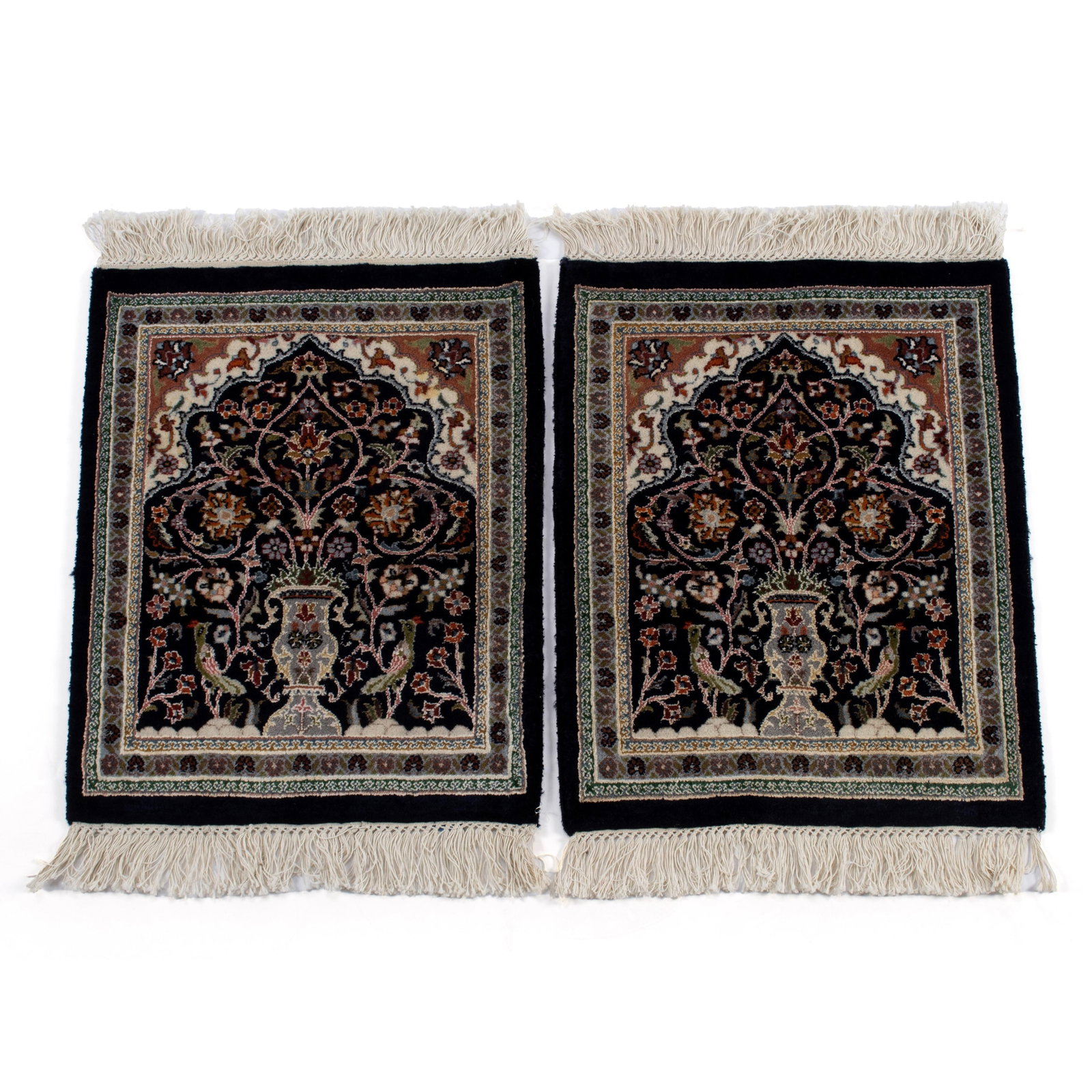 PAIR OF DIRECTIONAL MATS: PAIR OF DIRECTIONAL MATS Persian, 20th century, silk highlights. Each showing a flowering urn flanked by birds on the black field with ivory to soft red top corners, grey border with guard borders. 2 