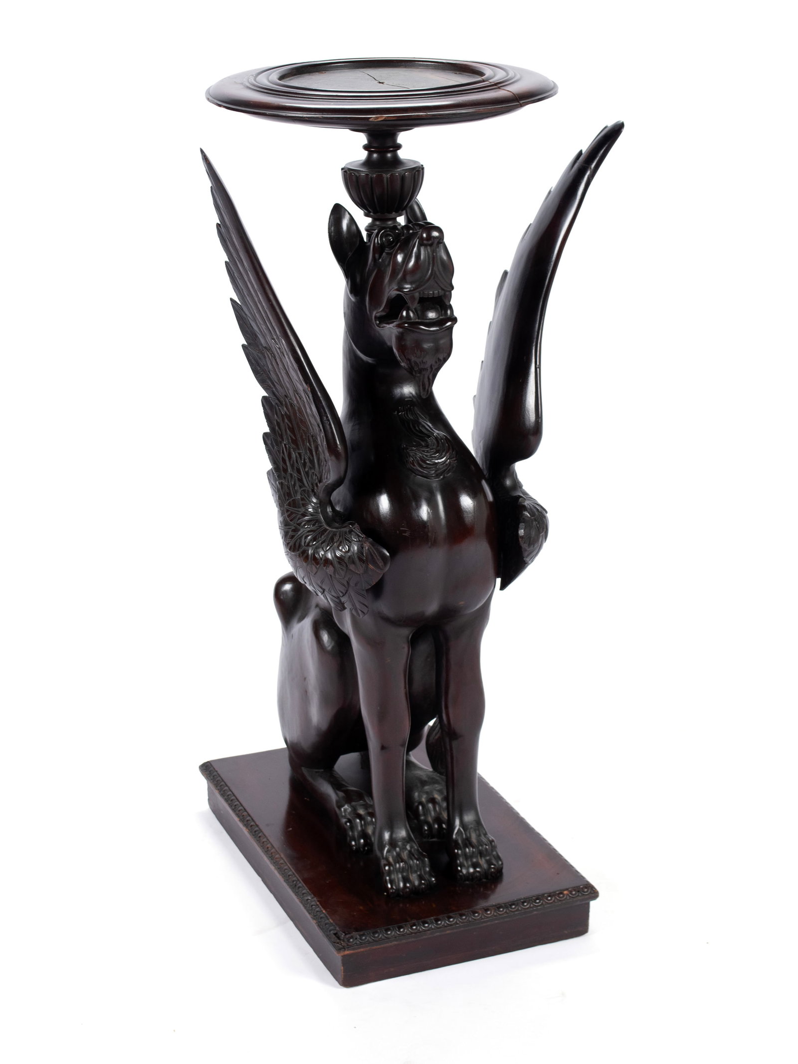 WINGED GRIFFIN FORM PEDESTAL: WINGED GRIFFIN FORM PEDESTAL American, mid-20th century, mahogany. Circular top over the full figural seated griffin with full wings displayed. On a rectangular base. 41 1/2 x 20 1/4 in. (105.4 x