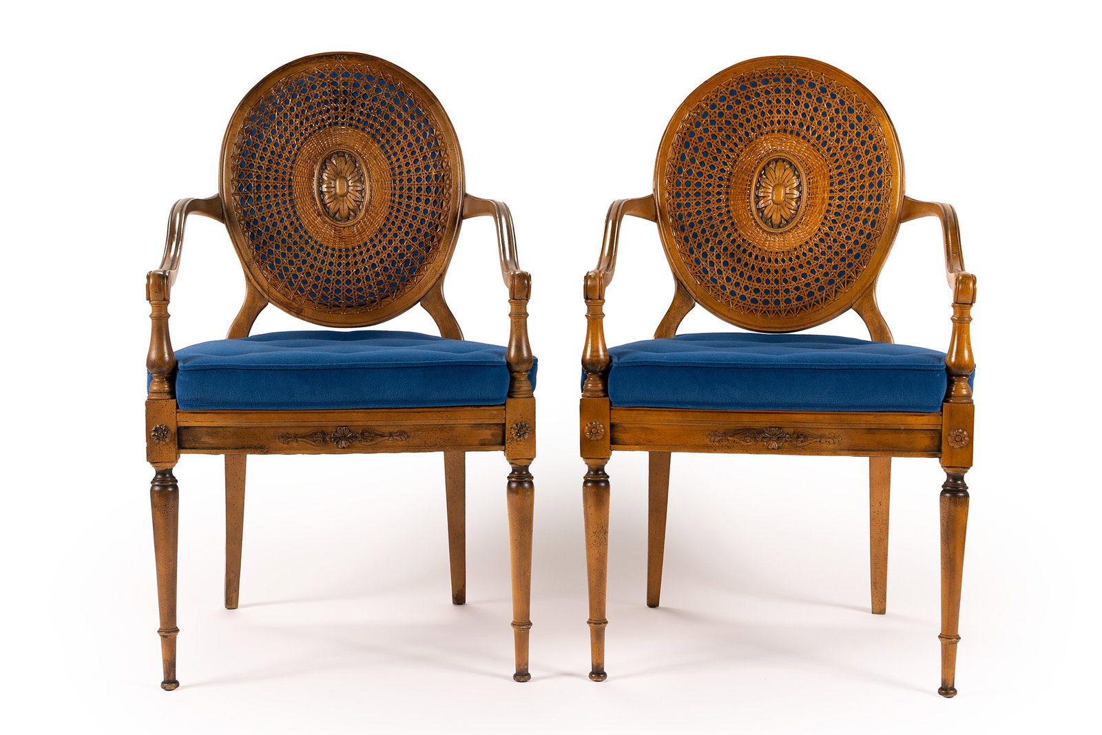 PAIR OF EDWARDIAN OPEN ARMCHAIRS: PAIR OF EDWARDIAN OPEN ARMCHAIRS English, early 20th century. Oval wicker backs with blue velvet backing and carved floral medallion to the center of each, over the matching padded seats, on tapering