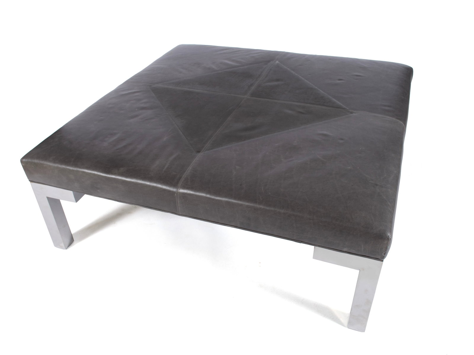 MITCHELL GOLD AND BOB WILLIAMS OTTOMAN: MITCHELL GOLD AND BOB WILLIAMS OTTOMAN American. Square leather cocktail ottoman with chrome legs, labeled to underside. 18 x 52 x 52 in. (45.7 x 132.1 x 132.1 cm.)