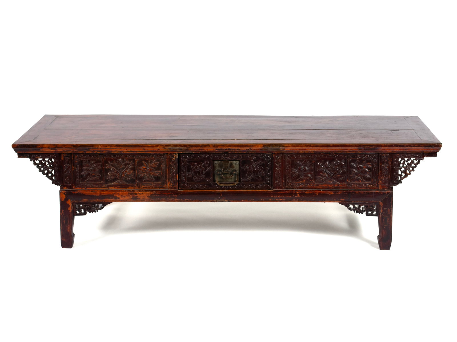 CARVED CHINESE LOW TABLE: CARVED CHINESE LOW TABLE Early 20th century, likely lacquered camphor. Rectangle form, relief carved panels and drawers with brass chrysanthemum pulls, pierced fretwork to corners, terminating on