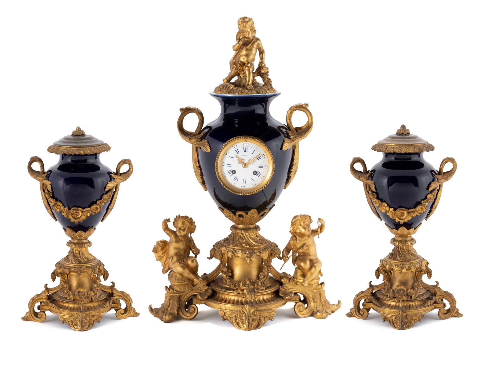 COLBALT BLUE GARNITURE SET: COLBALT BLUE GARNITURE SET French, 19th century. Centerpiece is a Ringuet mantel clock with elaborate gilt bronze, topped with a bronze cherub with two cherubs at the base. Two matching side urns with