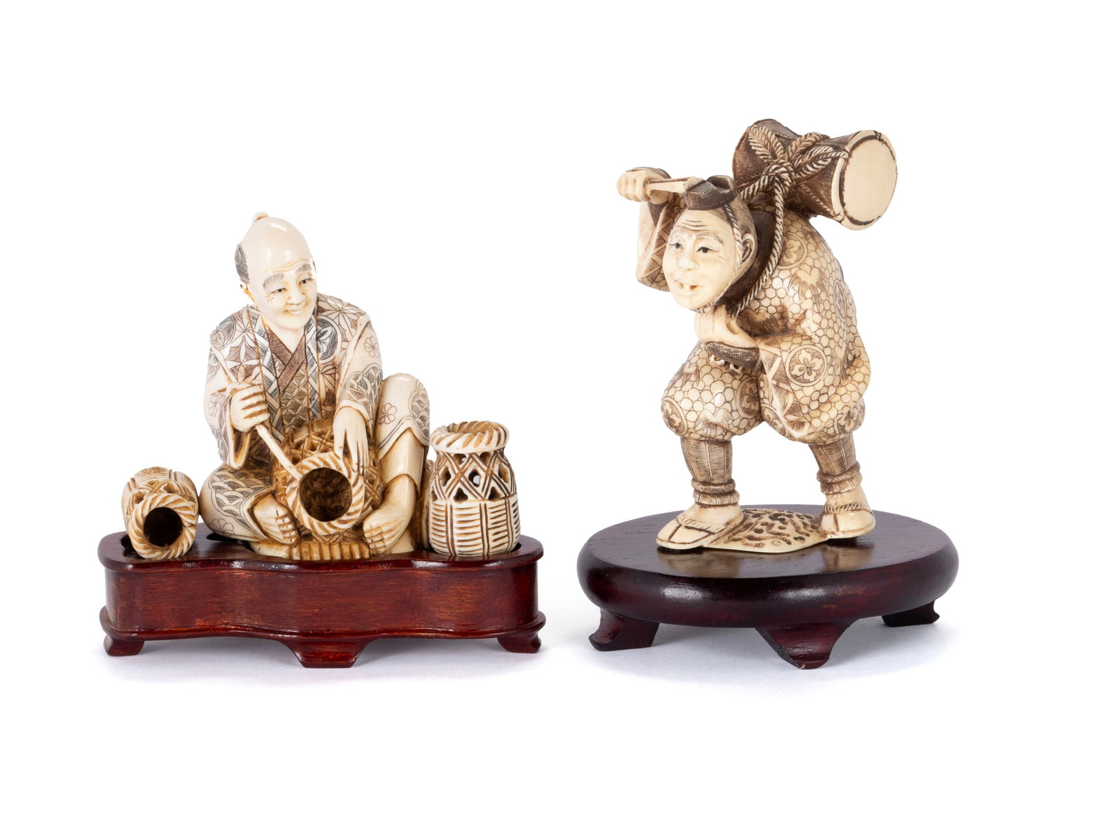 TWO JAPANESE CARVED FIGURES: TWO JAPANESE CARVED FIGURES Japanese, early 20th century. One perhaps a peddler with baskets as he is seated on the ground. The other perhaps a musician walking with a drum on his back. Tallest: 3