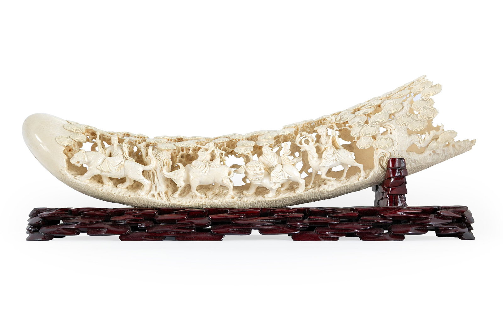 CHINESE FIGURAL CARVING: CHINESE FIGURAL CARVING Early 20th century. Detailed scene of figures riding animals through a woodland setting. Paired with a carved wooden stand. Tusk: 4 x 20 in. (10.2 x 50.8 cm.), Stand: 3 1/2 x