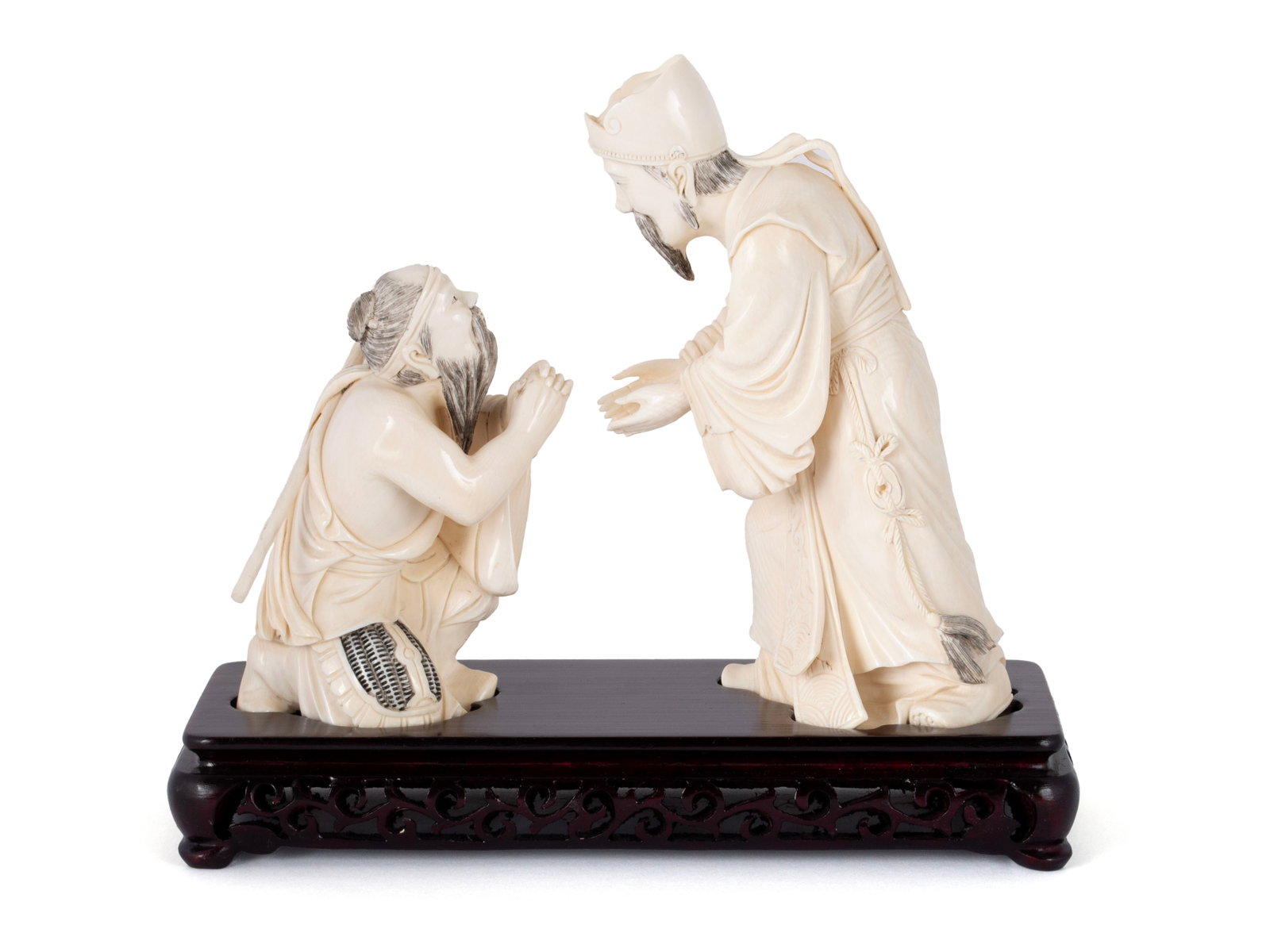 GROUP OF TWO FIGURAL CARVINGS: GROUP OF TWO FIGURAL CARVINGS Chinese, early 20th century, seal script marks underfoot. Showing a beggar kneeling in front of an elder. Tallest: 7 in. (17.8 cm.)
