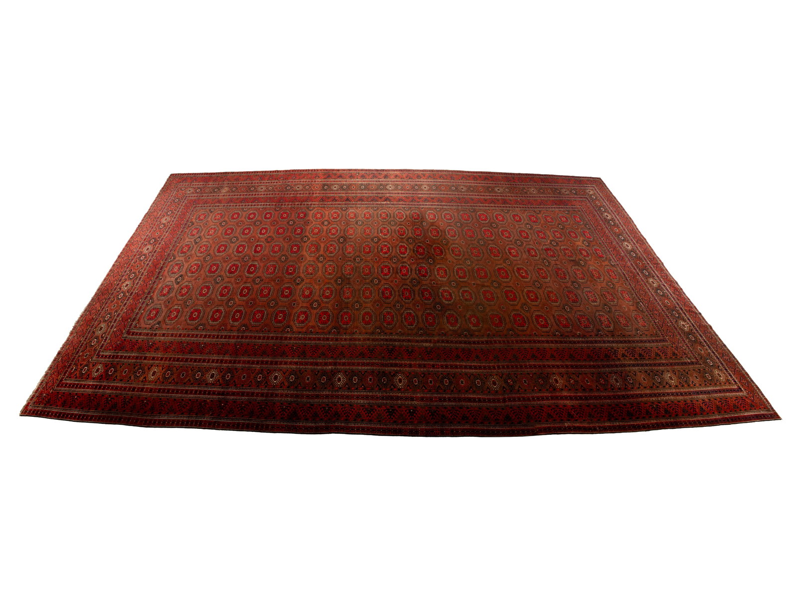 BOKHARA ROOM RUG: BOKHARA ROOM RUG Persian, 20th century. Repetitive rows of geometric medallions run the brick red field, multiple borders of brown and red decorated with foliate and geometric forms. 26 ft. 5 in. x