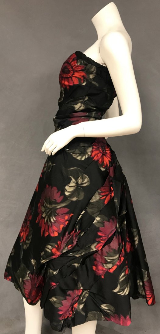 Rare Belgian Couture 1950s Silk Cocktail Dress: A stunning 1950's cocktail dress in black silk with a red and green floral. Strapless, elongated bodice with built in bustier. Dress has a semi-full skirt with beautifully pleated back and built in cr