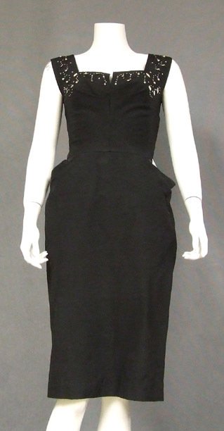 Black Faille 1950's Cocktail Dress w/ Rhinestones Pearl: Sleeveless bodice has a slit, square neckline dotted with prong set rhinestones, small metal studs, iridescent leaves and dangling faux pearls. Dress has a wiggling skirt with pleated hip pockets. Sid