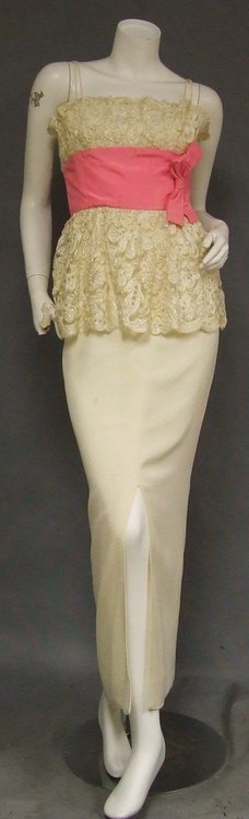 Wilson Folmar Cream Lace & Crepe 1960s Bombshell Dress: A stunning, early 1960's evening gown designed by Wilson Folmar. Fitted bodice and scalloped peplum are constructed of cellophane embroidered cream lace. Wide set-in waistband and bow of hot pink silk