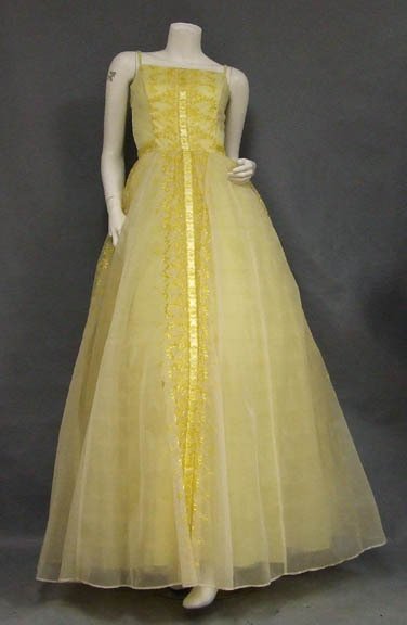 Yellow Chiffon 1960's Evening Gown w/ Embroidery: A charming 1960's evening gown in embroidered yellow nylon. Yellow satin ribbon applique down center of dres. Double spaghetti straps. Dress has a very full skirt with an attached ruffled crinoline. L