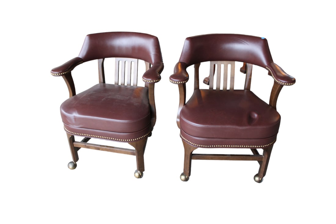 Pair of leather like arm chairs on rollers in a walnut frame: Pair of leather like arm chairs on rollers in a walnut frame, structurally sound and in good useable condition, see photos for noticeable issues, each 27"w x 24"d x 31"h with seat height of 19"