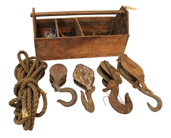 Antique wooden tool box with metal barn pulleys and rope.