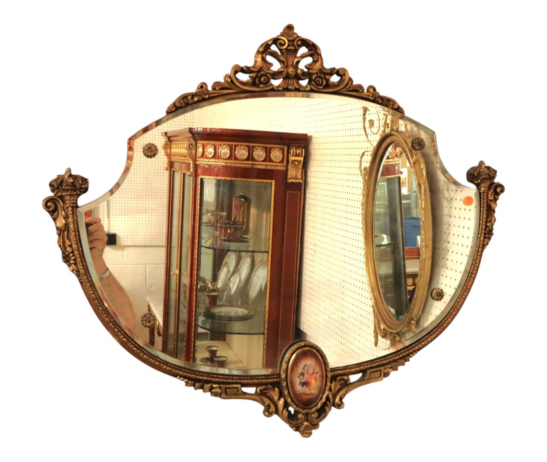 Vintage French Style Beveled Mirror Porcelain Plaque: Vintage French Provincial style gilt wall mirror. Features a contoured beveled glass plate, ornate acanthus crest, and an oval porcelain romantic couple portrait plaque. 29.5"H x 34"W x 1"D.