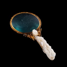 A gilded and gem-inlaid Hetian jade hand-held mirror from the Han Dynasty of China.