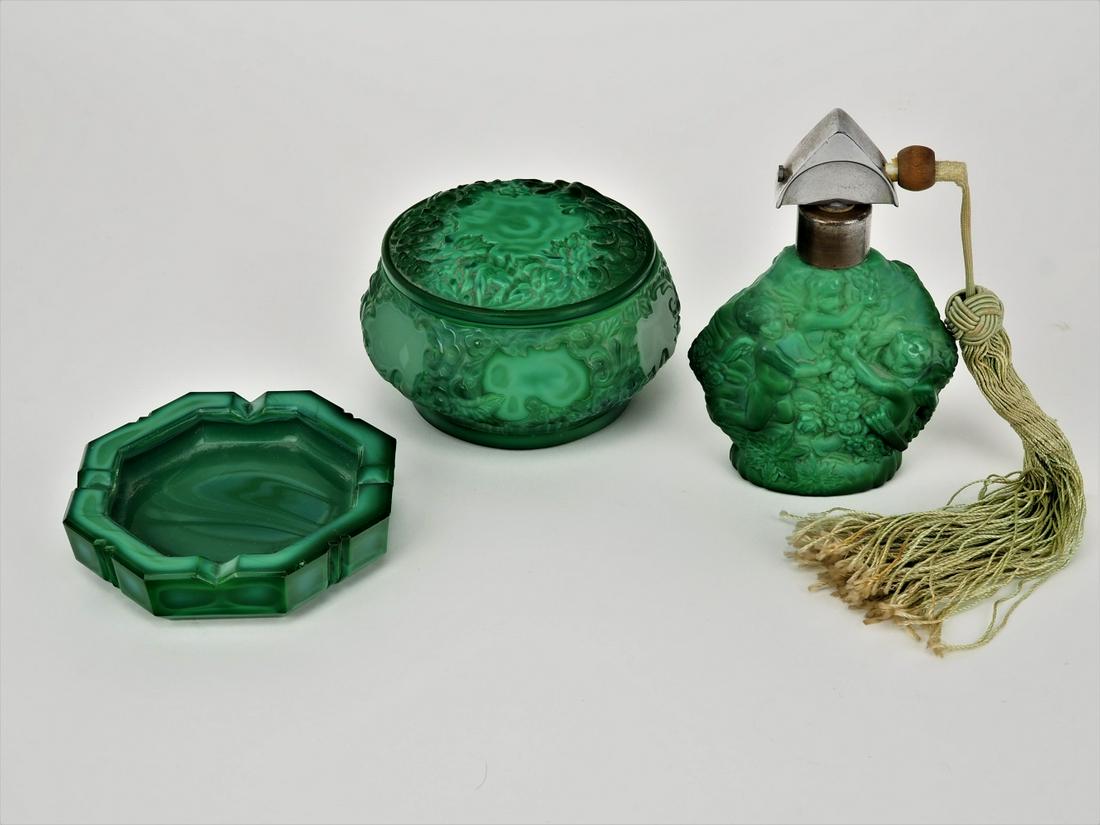Convolute malachite glass, 30's, 3 pieces: Convolute malachite glass, 30's, 3 pieces consisting of a perfume bottle, bulbous, flattened form with representation of several putti and flower tendrils, ground flat, spout with metal mount; an asht