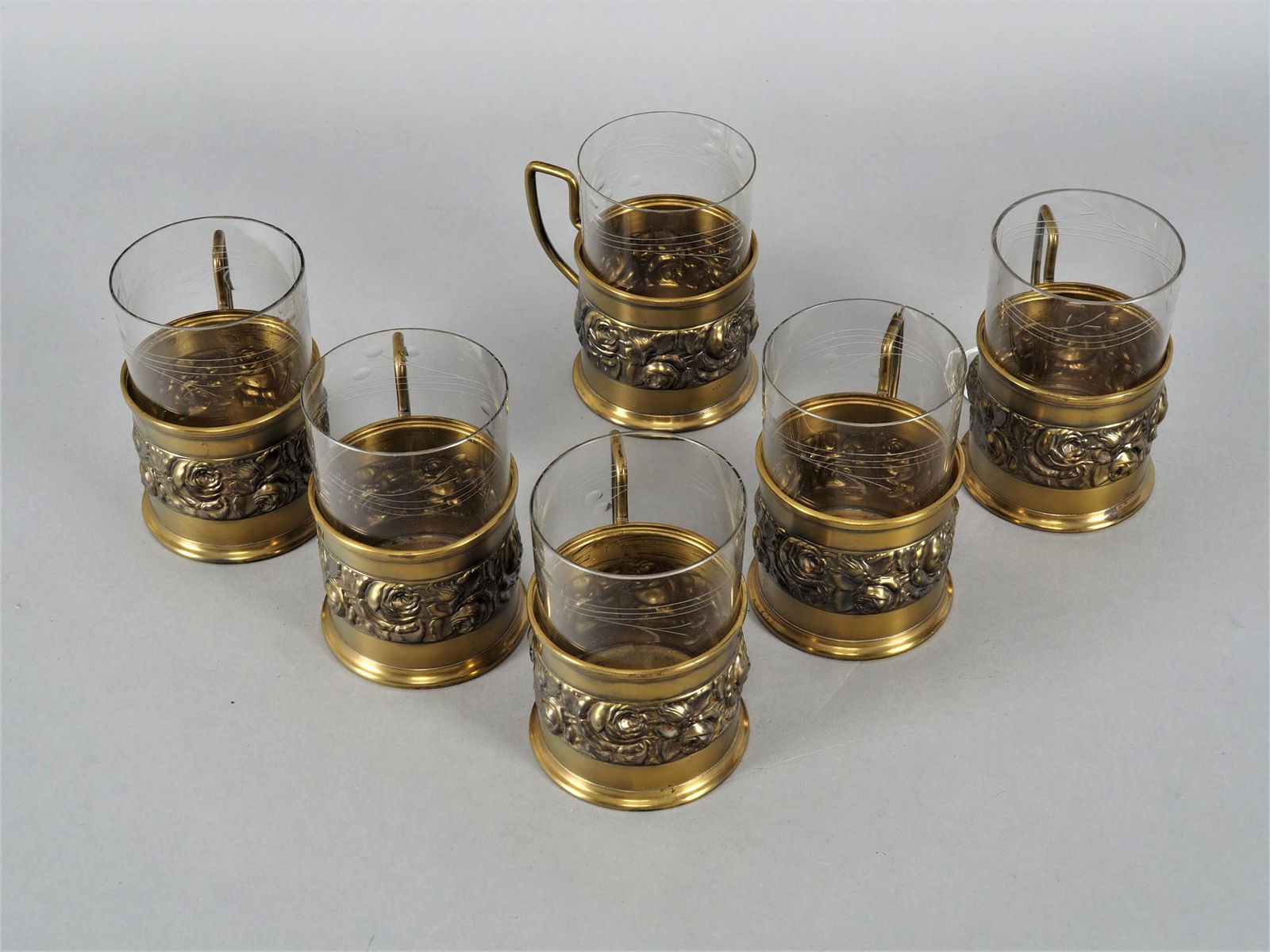Set of 6 Art Deco glasses: Set of 6 Art Deco glasses In metal holder with handles. Made of brass, centered with wide, slightly profiled floral frieze. Glass inserts made of thin clear glass in the upper part with cut motif. Ver