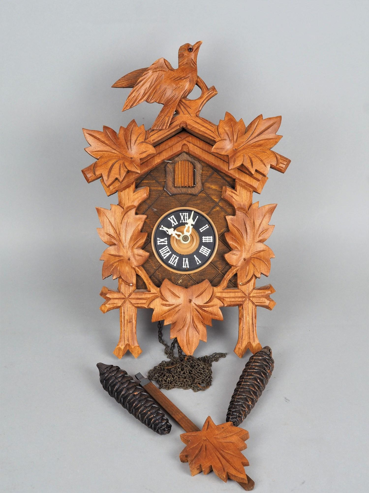 Modern cuckoo clock, probably 80s.: Modern cuckoo clock, probably 80s. Wooden case with carved front, movement with chain hoist and two weights and pendulum in leaf shape. Chiming movement on tone spiral and cuckoo call. Good complete c