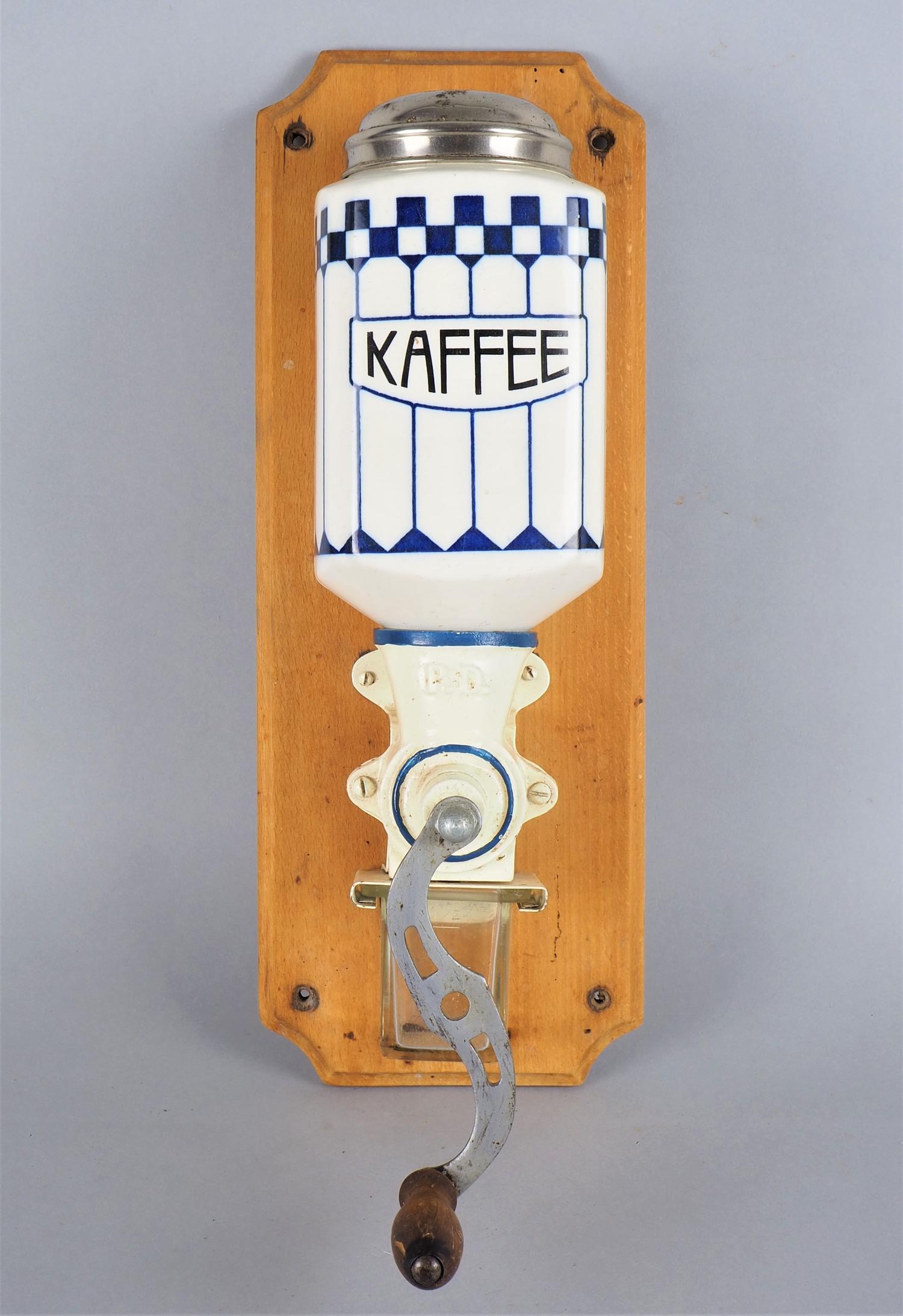 P.D. wall coffee grinder, around 1900.: P.D. wall coffee grinder, around 1900. Porcelain vessel with tin lid, bottom grinder with maker's mark "P.D.", with glass drip tray and original crank. Construction mounted on wooden wall bracket. L. 