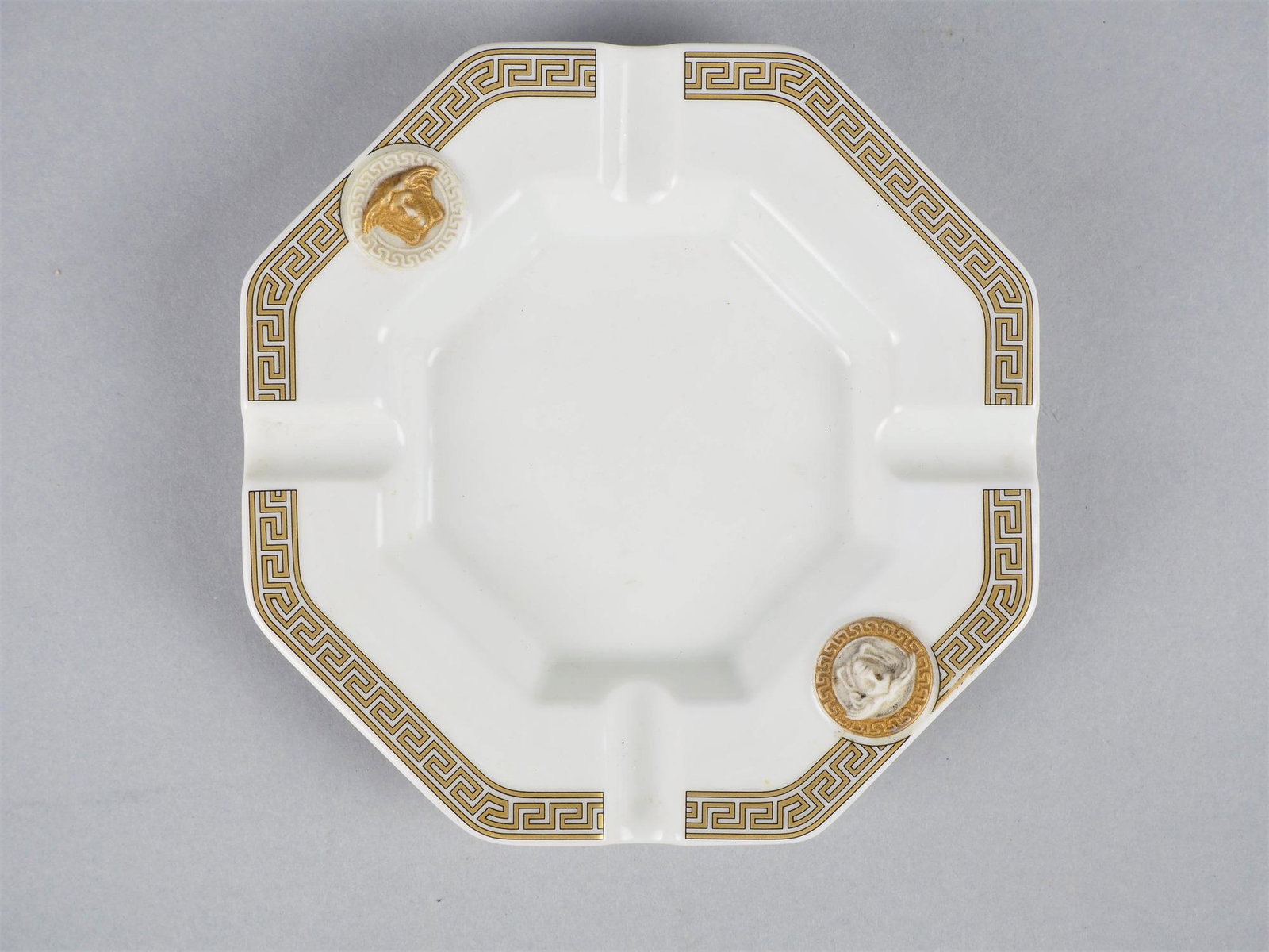 Versace / Rosenthal "Studio Line".: Versace / Rosenthal "Studio Line".Design "Versace" for "Rosenthal", model "Gorgona". Ashtray, porcelain, white glazed with gold staffage, intact. Ø 14cmVersace / Rosenthal "Studio Linie", Aschenb