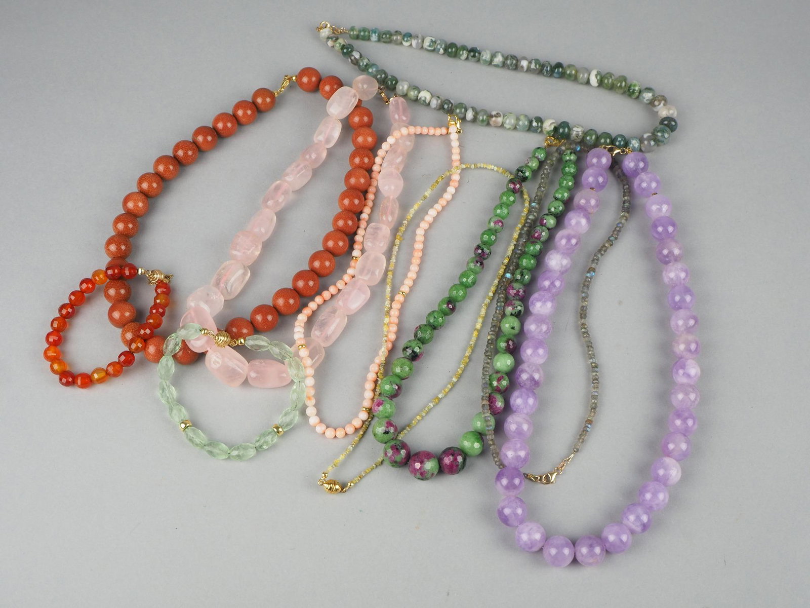 Convolute chains with 9kt. Gold clasps, 10 pieces: Convolute chains with 9kt. Gold clasps, 10 pieces8 necklaces and 2 bracelets, various gemstones a.o.: Rose quartz, rock crystal or amethyst, gold river, moss agate, zoisite, etc., total weight 567gKon