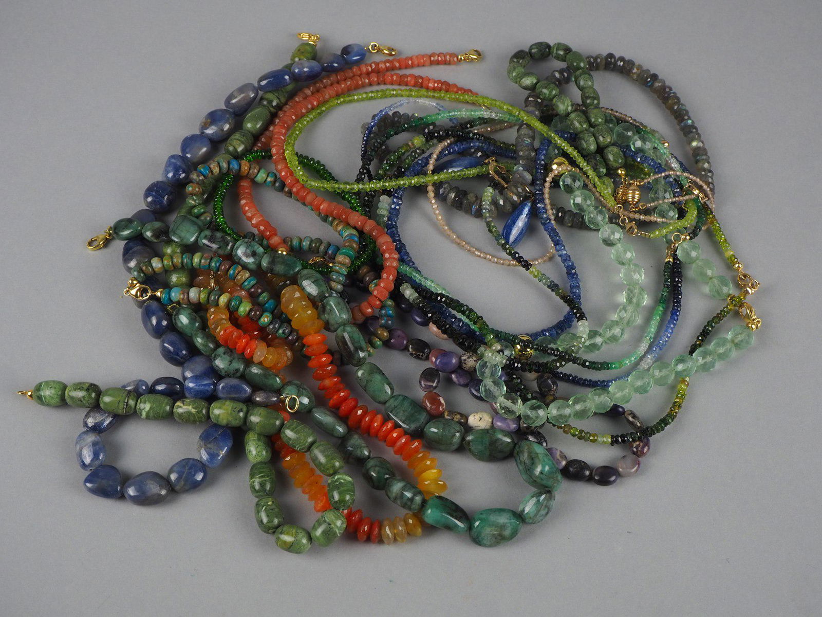 Convolute chains with 9kt. Gold clasps, weight 570g: Convolute chains with 9kt. Gold clasps, weight 570g16 necklaces, 2 bracelets and 1 pair of earrings, various gemstones a.o.: Sapphire, Jade/Nephrite, Agate, Aquamarine?, Labradorite, etc.Konvolut Kett