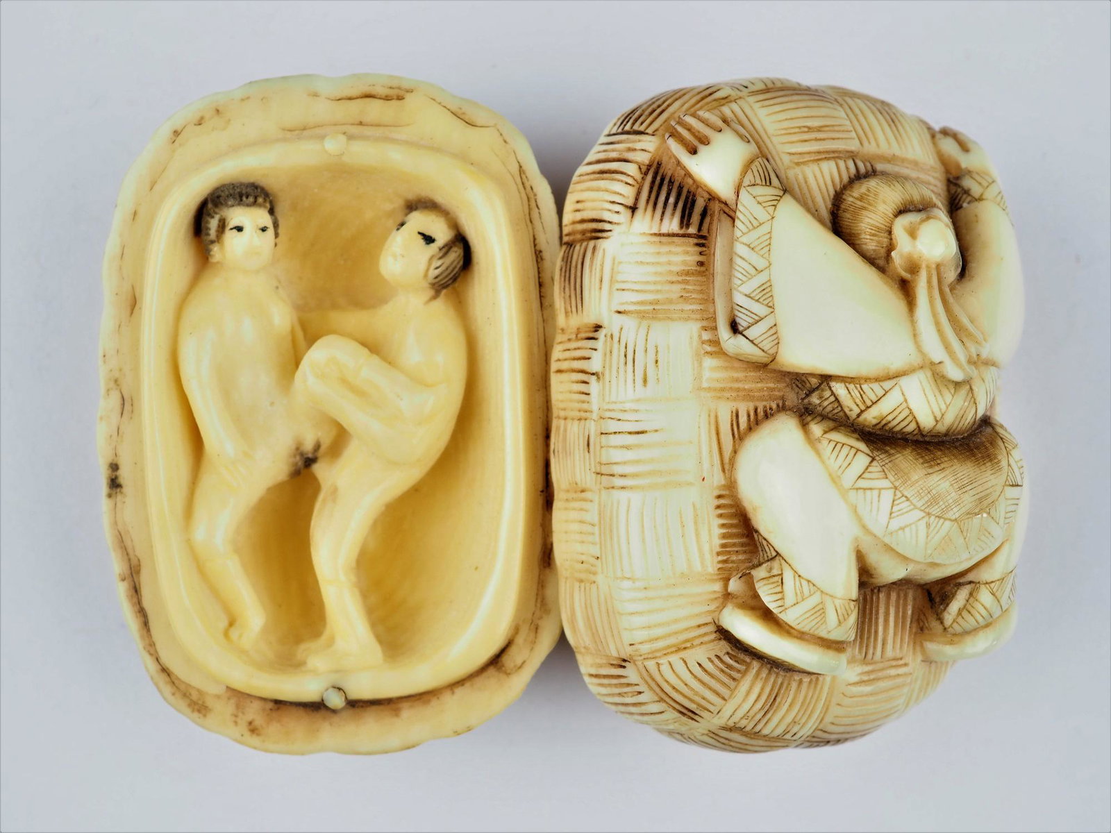 Antique erotic netsuke, c. 1900: Antique erotic netsuke, c. 1900Two-piece netsuke made of bone in the shape of a woven basket, on the lid of which a man watches a couple inside making love through an opening. Very finely crafted, ins