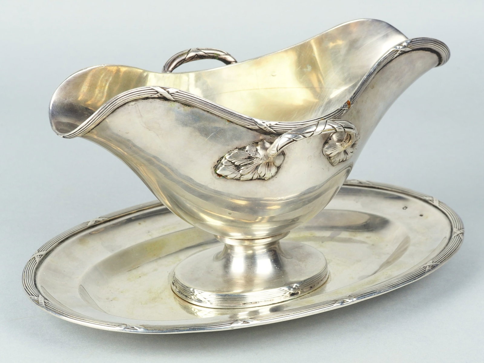 Silver gravy boat, neoclassicism, Vienna circa 1900: Silver gravy boat, neoclassicism, Vienna circa 1900Silver sauce boat screwed on oval saucer, curved shape with spout on both sides, profiled rims with cross band decor, handles on both sides ending to
